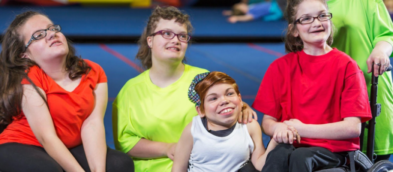 Image illustrant cinq enfants à mobilité réduite dans un gymnase. Ils sont souriants.