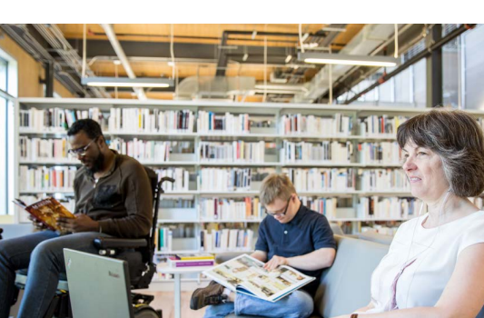 Photo utilisée en page couverture du Plan municipal AU 2024-2030. Présente trois personnes qui se détendent dans une bibliothèque. Une femme aveugle écoute un livre audio et deux hommes lisent. L'un d'eux vit avec une déficience intellectuelle et l'autre est en fauteuil roulant. 