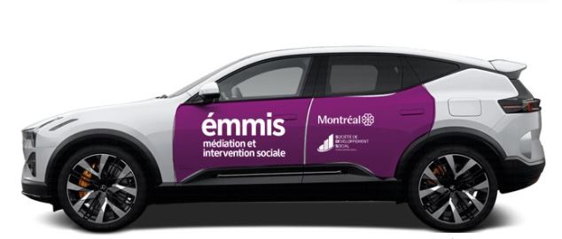 Voiture blanche avec les deux portes peinturées en mauve. Sur la porte du conducteur on peut lire : ÉMMIS médiation et intervention sociale' écrit en blanc. Sur la porte du passager derrière le conducteur on peut lire : Montréal avec le logo de la Ville.