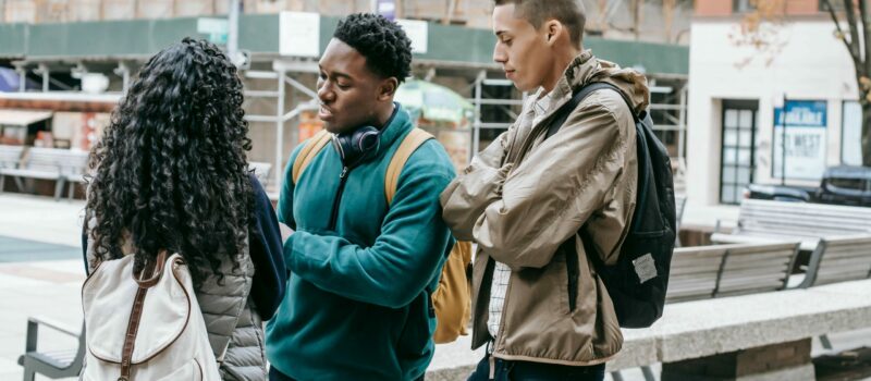 Trois jeunes discutent debout dans un espace public